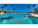 Large community swimming pool, featuring lounge chairs, clear blue water and tropical palm trees at 9304 Lake Chase Island Way, Tampa, FL 33626