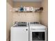Modern laundry room featuring a front load washer and dryer, and a wire shelf with cleaning supplies at 9628 Charlesberg Dr, Tampa, FL 33635