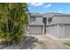 Inviting two-story townhouse featuring an attached garage, palm trees, and neutral siding at 9727 Tiffany Oaks Ln, Tampa, FL 33612