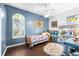 Well-lit bedroom featuring a ceiling fan, hardwood flooring, and a large window offering natural light at 10016 Oxford Chapel Dr, Tampa, FL 33647