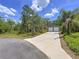 View of the detached two-car garage with a long concrete driveway amid lush greenery and a blue sky at 11470 Mahopac Rd, Weeki Wachee, FL 34614