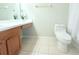 Bright bathroom featuring a toilet, tile floors, and a vanity with artificial flowers at 11622 Declaration Dr, Tampa, FL 33635