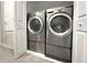 Modern laundry room with side-by-side washer and dryer and white tile floors at 11622 Declaration Dr, Tampa, FL 33635