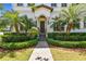 Charming home entrance featuring a brick walkway, lush greenery, and tropical palm trees at 134 Chesapeake Ave, Tampa, FL 33606