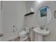 Powder room with a round mirror, shelving, toilet, and sink at 13539 Carryback Dr, Dade City, FL 33525