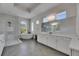 Luxurious bathroom featuring a soaking tub, large windows, a tiled shower, and white cabinets at 13539 Carryback Dr, Dade City, FL 33525