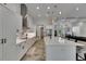 Modern white kitchen with stainless steel appliances, pendant lighting, and tile floors at 13539 Carryback Dr, Dade City, FL 33525