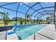 Beautiful pool area with a basketball hoop, landscaping and screen enclosure at 13539 Carryback Dr, Dade City, FL 33525