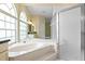 Bright bathroom featuring a marble tub with a large window and a glass-enclosed shower at 15314 Sherwood Forest Dr, Tampa, FL 33647