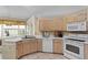 This is a kitchen with white appliances, light-colored wood cabinets, and a view to the outside at 15314 Sherwood Forest Dr, Tampa, FL 33647