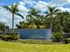 Beautiful entrance sign for The Vines at Cypress Creek surrounded by lush tropical landscaping and mature palm trees at 15426 Wicked Strong St, Sun City Center, FL 33573