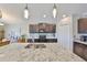 Kitchen island featuring granite countertops, stainless steel sink, pendant lighting, and lots of bar stool seating at 15426 Wicked Strong St, Sun City Center, FL 33573