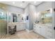Bright bathroom with white cabinets, marble countertops, and large mirrors over dual vanities with a tiled glass shower at 17305 Ballmont Park Dr, Odessa, FL 33556