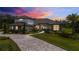 Stunning exterior showcasing stone accents, tile roof, paver driveway, and professional landscaping under a vibrant sunset sky at 17305 Ballmont Park Dr, Odessa, FL 33556