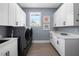 Functional laundry room with white cabinets, a large sink, quartz countertop, and modern washer/dryer units at 17305 Ballmont Park Dr, Odessa, FL 33556