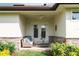 Covered outdoor patio with stone accents, comfortable couch, glass table, and lush landscaping at 17305 Ballmont Park Dr, Odessa, FL 33556