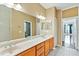 Bright bathroom featuring double sink vanity with wood cabinets, decorative lighting, and a view to additional rooms at 17812 Arbor Greene Dr, Tampa, FL 33647