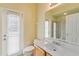 Bright bathroom features a door to the pool, white vanity, and neutral tile flooring at 17812 Arbor Greene Dr, Tampa, FL 33647