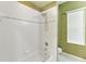 Bathroom featuring a shower-tub combo with white tile walls and accent trim, complemented by decorative green wallpaper at 17812 Arbor Greene Dr, Tampa, FL 33647
