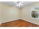 An empty bedroom with hardwood floors, a ceiling fan, and window at 17812 Arbor Greene Dr, Tampa, FL 33647
