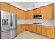 Corner of kitchen with stainless steel fridge, wood cabinets, and white countertops at 17812 Arbor Greene Dr, Tampa, FL 33647