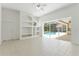 Open living room with a built-in shelving unit and sliding glass doors leading to the pool at 17812 Arbor Greene Dr, Tampa, FL 33647