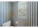 Stylish powder room featuring blue and white striped wallpaper and a white toilet, offering a fresh and clean design at 17812 Arbor Greene Dr, Tampa, FL 33647