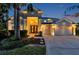Stunning home exterior featuring a three-car garage, lush landscaping, and exterior lighting at dusk at 19055 Lone Creek Ct, Land O Lakes, FL 34638