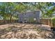 Backyard with the back of the house, an air conditioning unit, wood fence, and large shade trees at 3115 W Wyoming Ave, Tampa, FL 33611