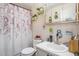 Cozy bathroom with floral shower curtain, plants on shelves, and neutral tiles at 3115 W Wyoming Ave, Tampa, FL 33611