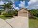 Well-kept single-story home featuring a desert landscape, mature palms, and two-car garage at 3254 Grassglen Pl, Wesley Chapel, FL 33544