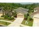 Well-maintained home featuring a two-car garage, landscaped front yard with tropical plants, and wide driveway at 3254 Grassglen Pl, Wesley Chapel, FL 33544