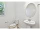 Bright powder room with pedestal sink, oval mirror, and natural light from the window at 37194 Clinch Cir, Zephyrhills, FL 33540