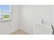 Functional laundry area with a utility sink, window providing natural light and neutral-colored tile at 37194 Clinch Cir, Zephyrhills, FL 33540