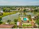 Aerial view featuring a community pool, shuffleboard courts, and access to a picturesque lake at 4016 Lighthouse Way, New Port Richey, FL 34652
