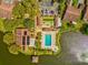 Aerial view featuring a community pool, shuffleboard courts, parking, and access to a picturesque lake at 4016 Lighthouse Way, New Port Richey, FL 34652