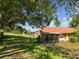 A home's backyard features a patio with a screen, spacious yard, mature landscaping, and a glimpse of the neighborhood at 4016 Lighthouse Way, New Port Richey, FL 34652