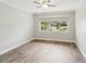 Bright, empty bedroom with wood-look floors, a ceiling fan, and a large window at 4016 Lighthouse Way, New Port Richey, FL 34652