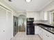 Kitchen with black appliances, white cabinets, tile floors and an archway leading to the living room at 4016 Lighthouse Way, New Port Richey, FL 34652