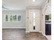 Bright living room featuring wood-look floors, white trim, and a front door at 4016 Lighthouse Way, New Port Richey, FL 34652