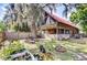 Expansive backyard view featuring a charming log cabin-style home with lush landscaping and trees at 4126 Burrows Rd, Zephyrhills, FL 33542