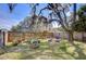 Fenced backyard featuring lush greenery, mature trees and cozy patio seating for outdoor relaxation at 4126 Burrows Rd, Zephyrhills, FL 33542