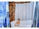 Bathtub with decorative shower curtains and stylish fixtures, surrounded by stone-look and wood walls at 4126 Burrows Rd, Zephyrhills, FL 33542