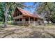 Charming two-story log home featuring a metal roof, wraparound porch and mature trees at 4126 Burrows Rd, Zephyrhills, FL 33542