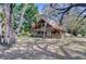 Charming two-story log home featuring a metal roof, wraparound porch and mature trees at 4126 Burrows Rd, Zephyrhills, FL 33542