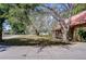 Spacious front lawn with mature trees, leading to a cozy log cabin home at 4126 Burrows Rd, Zephyrhills, FL 33542