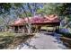 Charming log cabin-style home with a red roof, front porch, and covered parking area at 4126 Burrows Rd, Zephyrhills, FL 33542