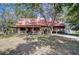 Charming log cabin-style home with a red roof, front porch, and a spacious front yard at 4126 Burrows Rd, Zephyrhills, FL 33542