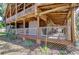 Exterior view of a log cabin with an inviting porch and lattice work, enhanced by greenery and a stone fireplace at 4126 Burrows Rd, Zephyrhills, FL 33542