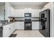Modern kitchen with white cabinets, granite countertops, sleek black appliances, and tile flooring at 4550 Globe Thistle Dr, Tampa, FL 33619